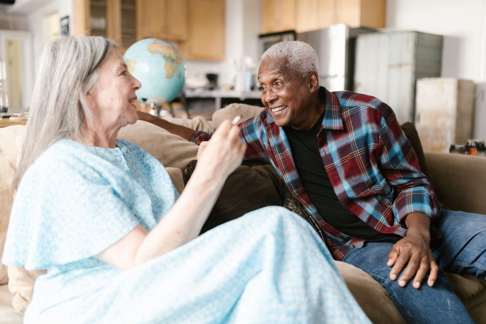 Joyful elderly couple sharing a warm moment at home, smiling and talking.