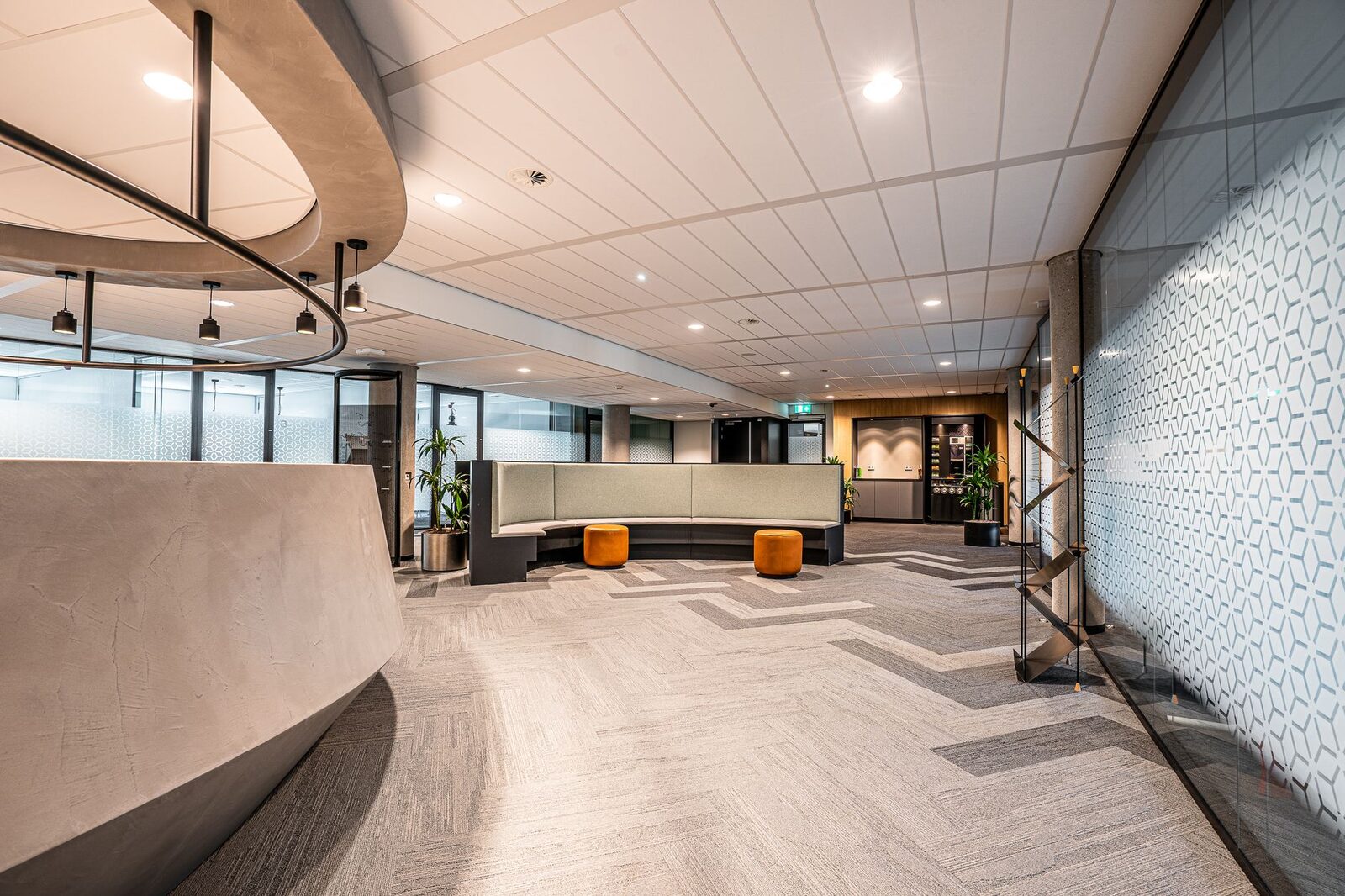 Spacious modern office lobby featuring minimalist interior design with seating and decorative lighting.